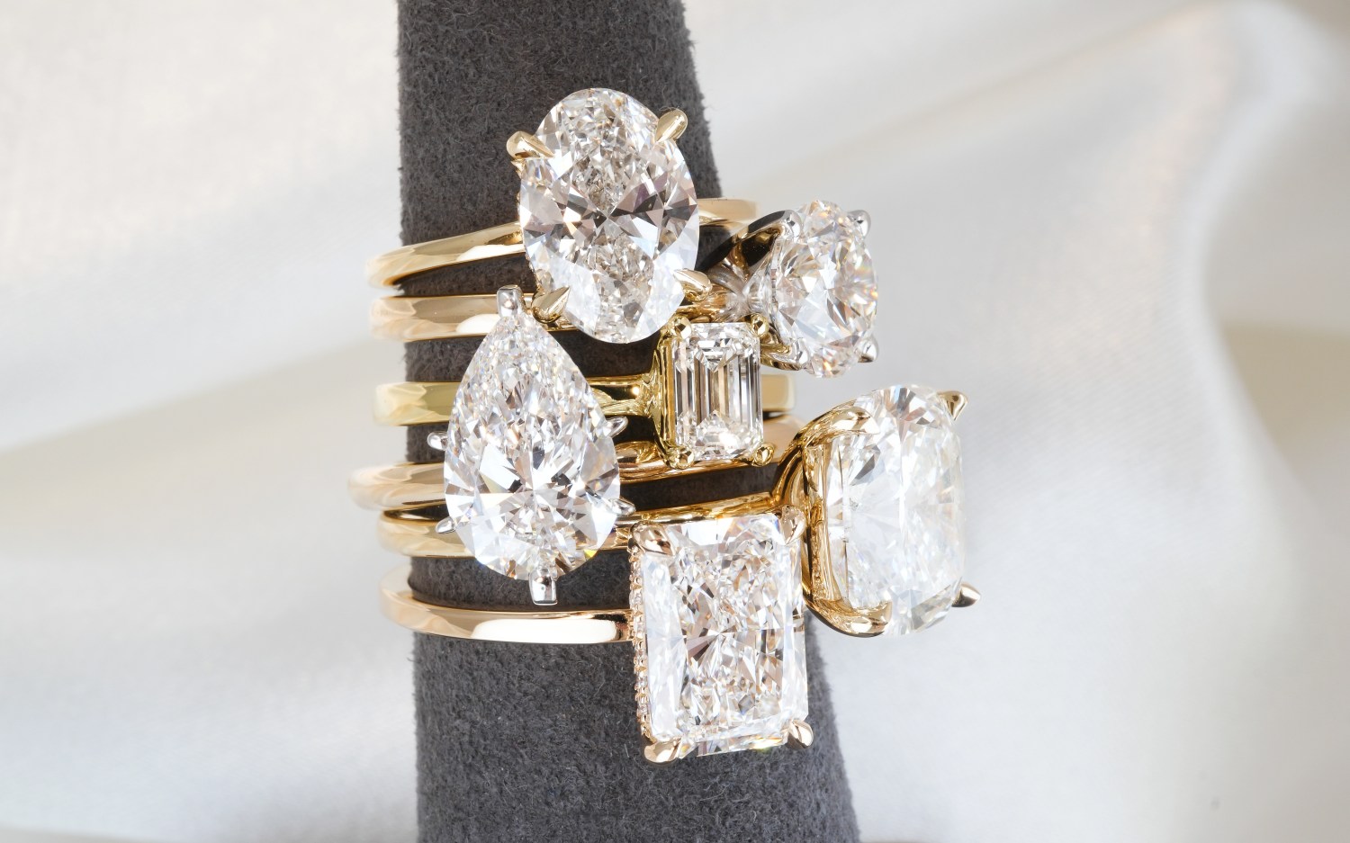 A ring holder stacked with six diamond rings of various shapes and sizes from Do Amore
